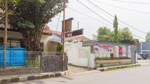 Propiedad resguardada por un muro de piedra, una valla metálica y un lona azul cubriendo algunos objetos.