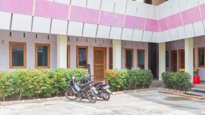 Un edificio con varias puertas, con los números 102 y 105, y una motocicleta estacionada al frente.