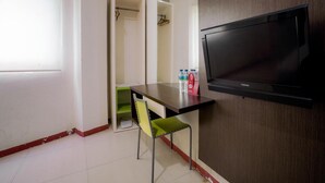 Une petite pièce avec un téléviseur, une table, une chaise et une armoire.