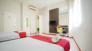 Une chambre d’hôtel avec deux lits, une t élévision, un miroir et un petit bureau avec une chaise.