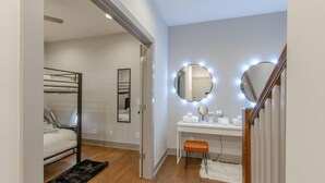 Ein Schlafzimmer mit Etagenbett, Schminktisch mit Spiegeln und einem kleinen Hocker.