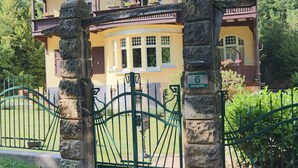 Una puerta de piedra con un letrero del número 6, que da paso a un edificio amarillo con un balcón y ventanas.