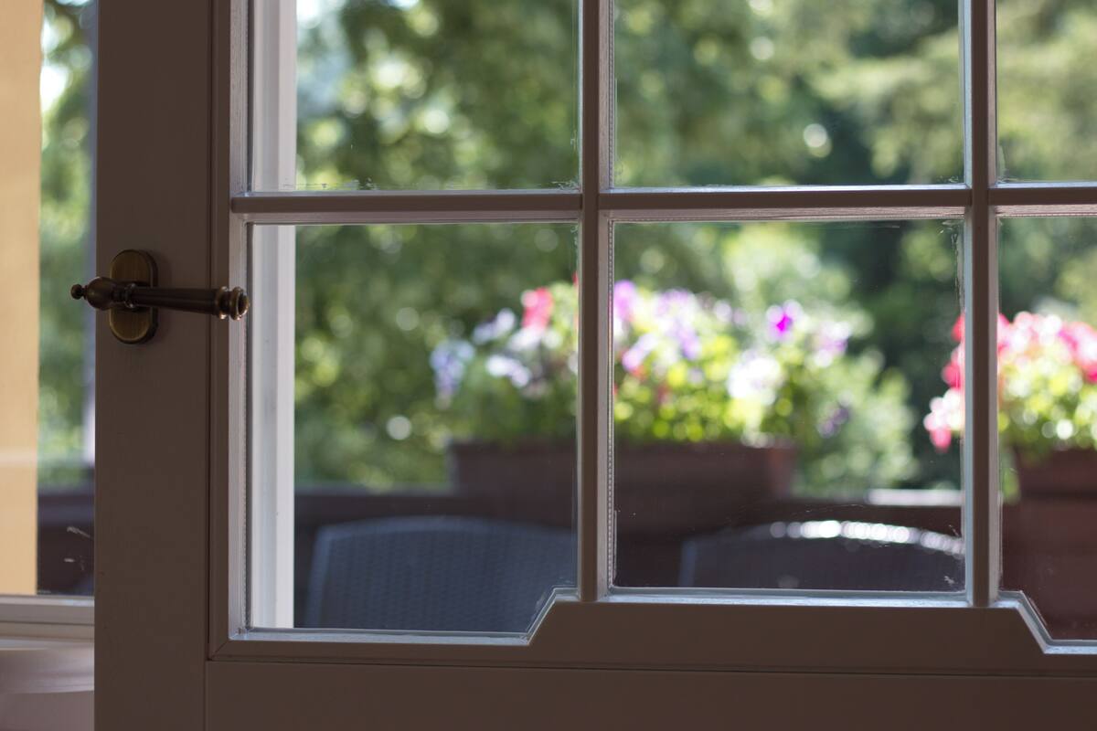 Puerta con ventana, desde donde se ve un jardín lleno de flores.