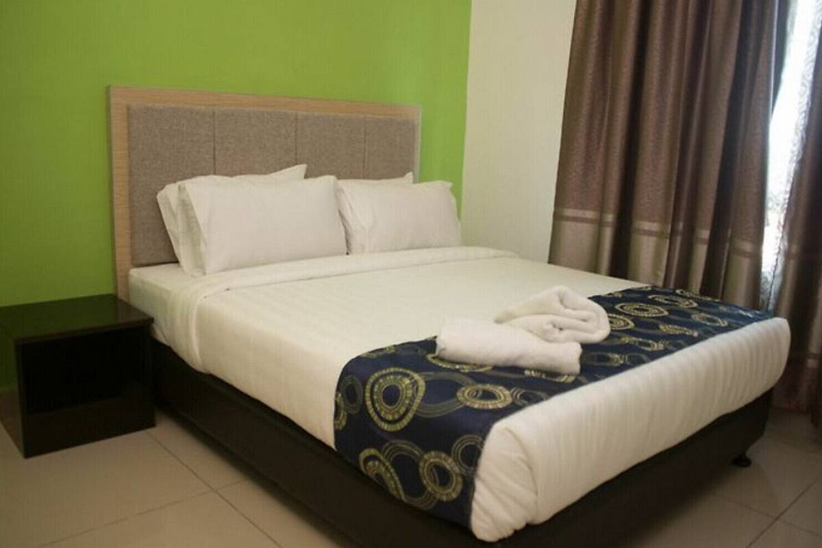 A neatly made bed with white linens and a blue patterned throw blanket, a wooden headboard, and a small bedside table.