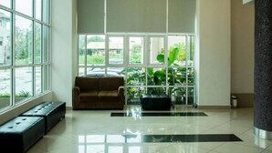 A spacious lobby with large windows, a sofa, and a bench. - De' Viana Hotel & Apartment (Kota Bharu)