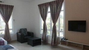A hotel room with a bed, a sofa, a small table, a TV on the wall, and large windows with curtains. - De' Viana Hotel & Apartment (Kota Bharu)