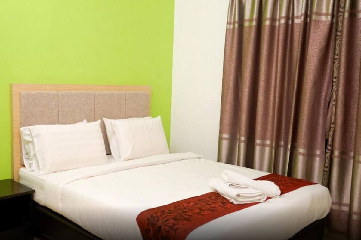 A hotel room with a bed, a nightstand, and a curtain.
