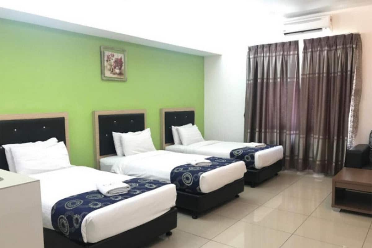 A hotel room with three single beds, a desk, and a chair.