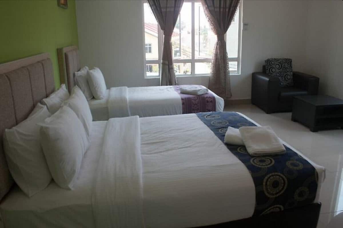 A hotel room with two beds, a small sofa, and a window with curtains.