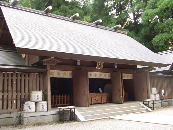 Edificio japonés tradicional con tejado de tejas, pilares de madera y un pequeño acceso con escalones.
