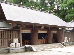 A traditional Japanese building with a tiled roof, wooden pillars, and a small entrance area with steps leading up to it. - Hotel Grateful Takachiho (Takachiho)