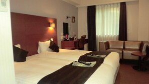 Een hotelkamer met een groot bed, een bureau, een stoel en een bank.