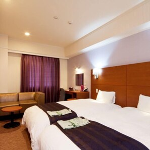 Una habitación de hotel con cama, sofá, una mesita y un escritorio con silla.