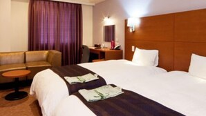 Une chambre d’hôtel comprenant un lit, un canapé, une petite table et un bureau avec une chaise.