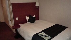 A hotel room with a large bed, a round bedside table, a red headboard, and a wall-mounted lamp. - Hotel Grateful Takachiho (Takachiho)