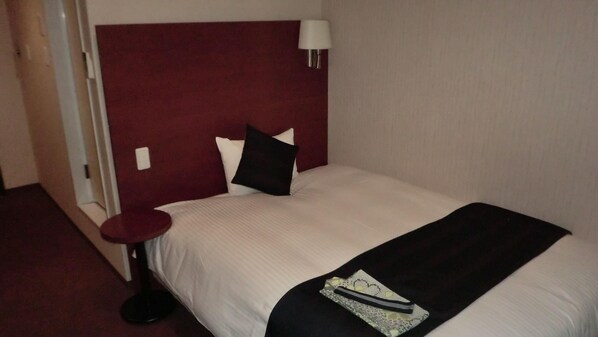 A hotel room with a large bed, a round bedside table, a red headboard, and a wall-mounted lamp. - Hotel Grateful Takachiho (Takachiho)