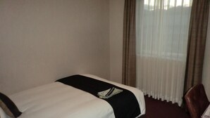 Une chambre d’hôtel avec un lit, une chaise et une fenêtre avec des rideaux.