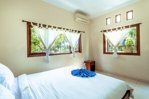 A hotel room with two windows, a bed, a nightstand, and an air conditioning unit. - Teba House Bisma Ubud by Ecommerceloka (Ubud)