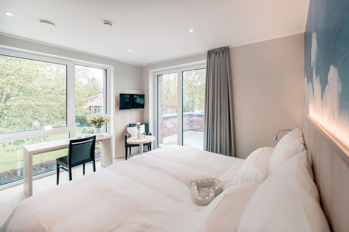 A modern bedroom with a large bed, a desk, and a TV.