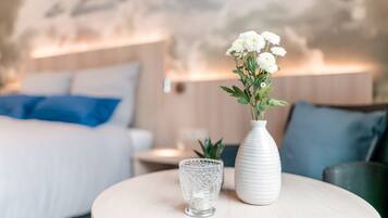 Ein Schlafzimmer mit einem Bett, einem Nachttisch, einer Vase mit Blumen und einer Lampe.