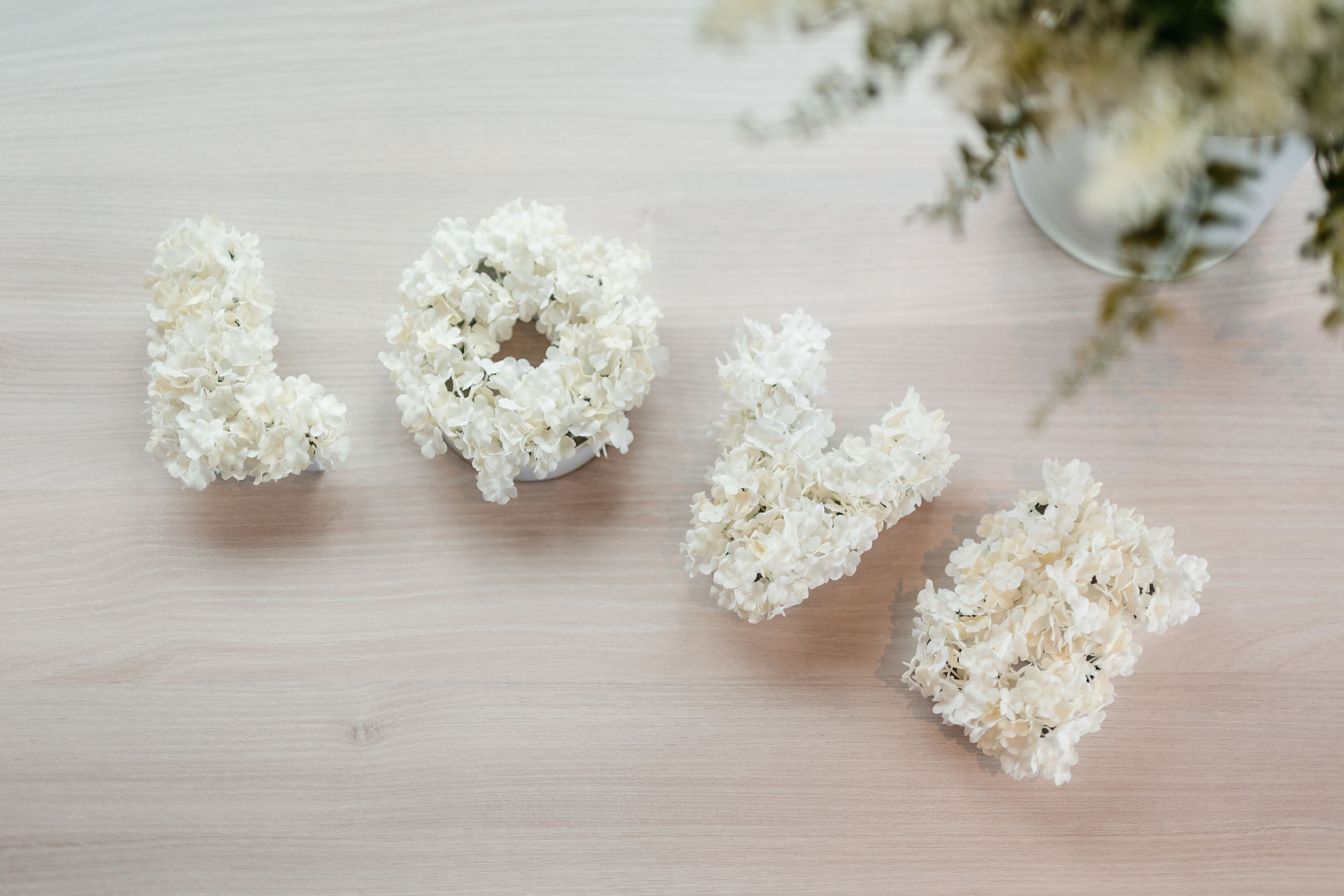 A wooden surface with clusters of white flowers arranged to spell "LOVE".
