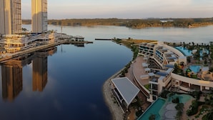Ett högt hotell med utsikt över vattnet, en swimmingpool och en brygga.