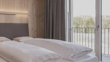 Ein modernes Schlafzimmer mit einem großen Bett, einem Holzkopfende und einer Schiebeglastür, die auf einen Balkon führt.