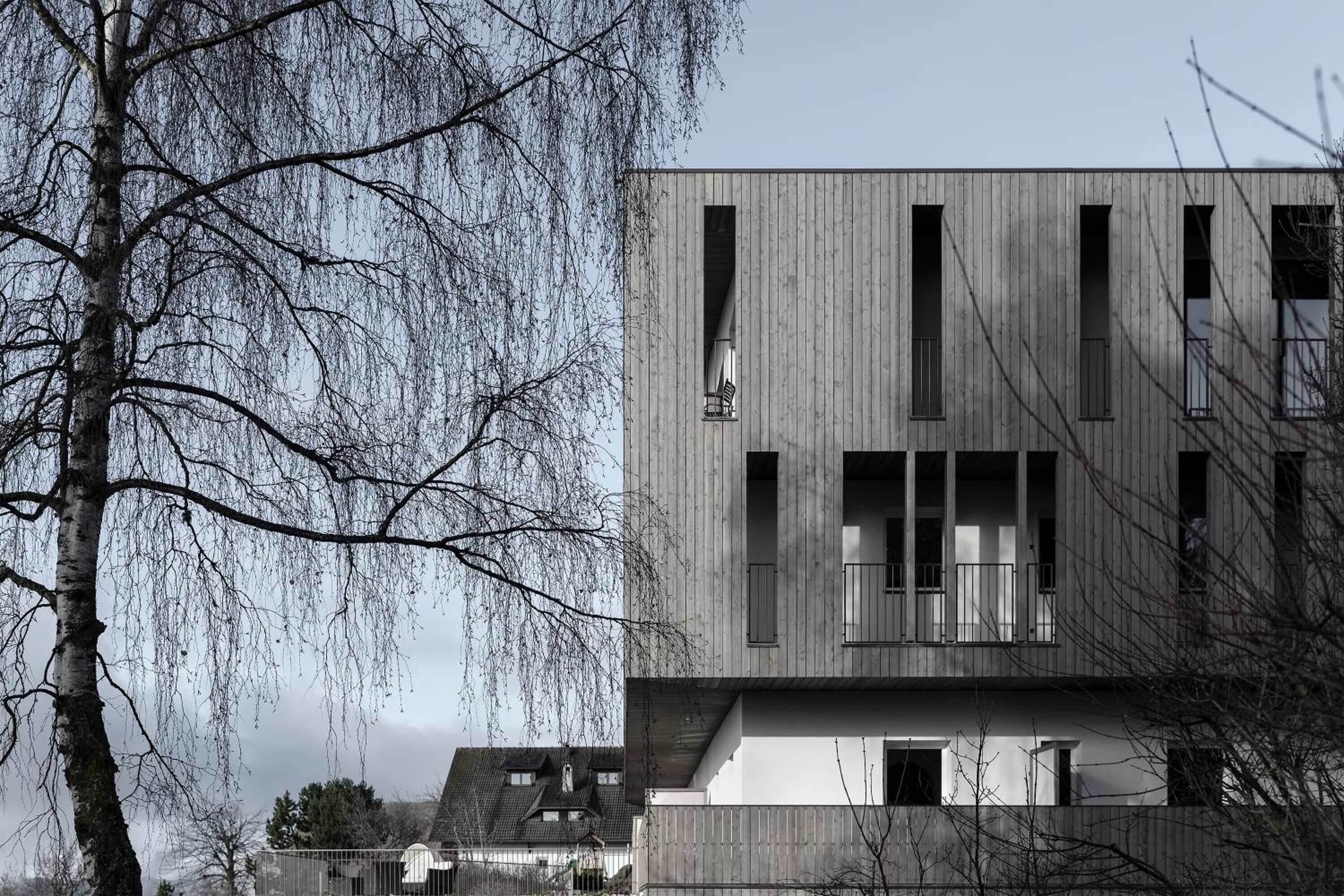 A modern building with a wooden facade, multiple balconies, and large windows.