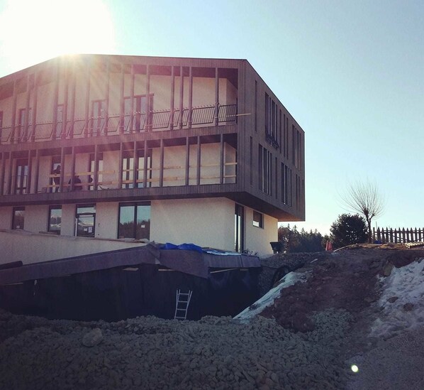 A modern building under construction with multiple floors, large windows, and a flat roof.