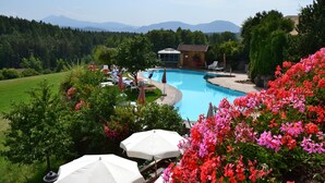 Una piscina rodeada de exuberante vegetación y flores, con vistas a una montaña al fondo.