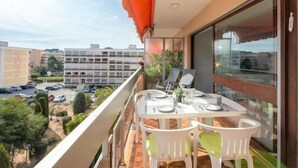 A balcony with a table set for dining, overlooking a parking area and buildings. - Le Maxime by Interhome (Sainte Maxime)