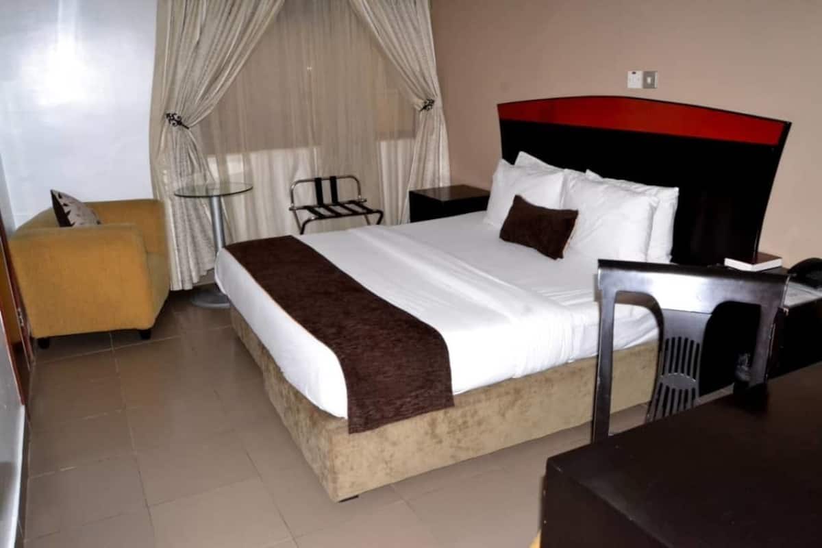 Ein Hotelzimmer mit einem Bett, einem Nachttisch, einem Stuhl und einem kleinen Tisch.
