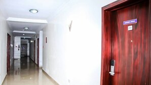 Ein Hotelkorridor mit poliertem Boden, einer Holztür mit Namensschild und einer Nummer.'