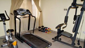 Ein Heimfitnessraum mit Laufband, Ergometer und einer Gewichtshalterung.