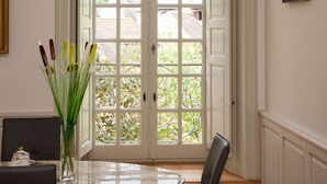 A room with a large bay window, a dining table with chairs, and a vase with flowers. - APARTMENT OF STANDING THE GENIS (Sarlat-la-Canéda)