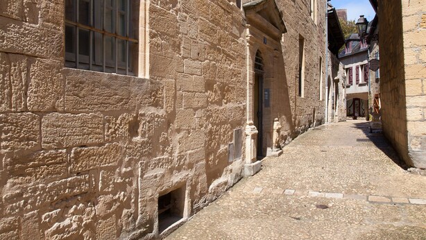 A narrow cobblestone street flanked by historic stone buildings with large windows and arched doorways. - APARTMENT OF STANDING THE GENIS (Sarlat-la-Canéda)