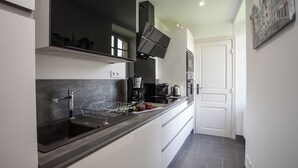 A modern kitchen with a black countertop, stainless steel appliances, and a white door. - APARTMENT OF STANDING THE GENIS (Sarlat-la-Canéda)