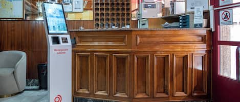 A reception area with a wooden counter, a digital kiosk, and a sign indicating WiFi availability.