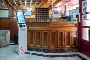 Ein Empfangsbereich mit Holztresen, einem digitalen Kiosk und einem Schild, das kostenloses WLAN anzeigt.