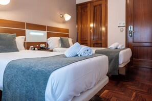 Ein Hotelzimmer mit zwei Betten, Holz-Kopfteilen, einem Schrank aus Holz und einem Nachttisch mit Lampe.