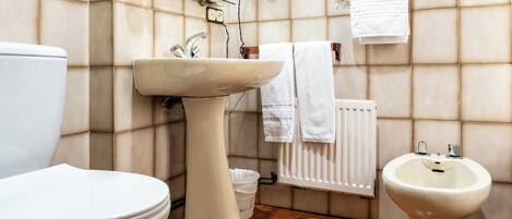 A bathroom with a toilet, sink, and bidet.