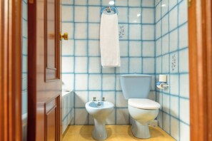 A bathroom with a toilet, bidet, and a towel hanging on a rack.