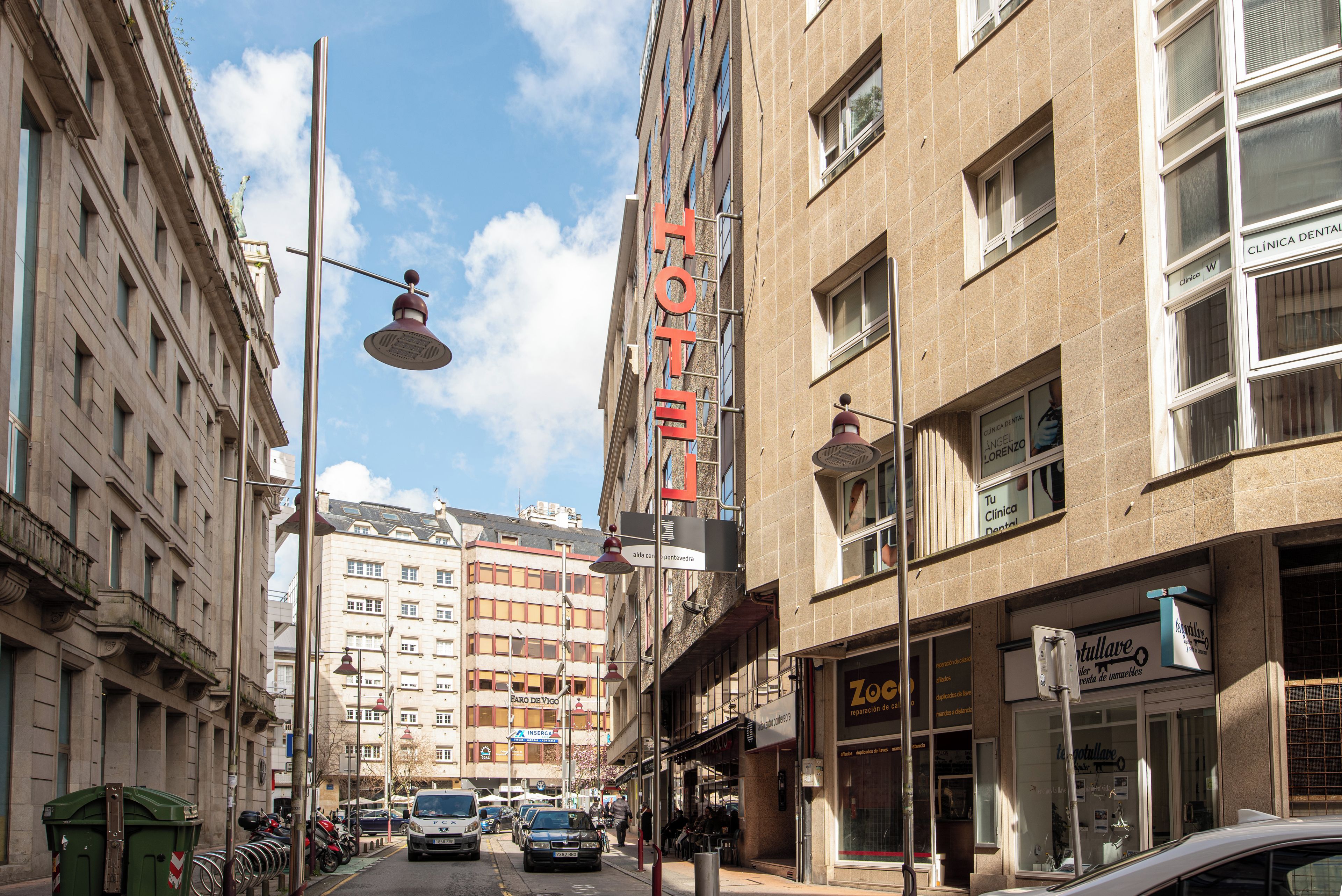 Un hotel con un cartel llamativo que dice 'HOTEL', un local con la señalización 'Zoccolo' y un cartel de 'Clínica Dental'.