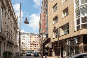 A hotel with a prominent 'HOTEL' sign, a storefront with 'Zoccolo' signage, and a 'Clinica Dental' sign.
