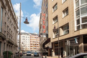 Un hotel con un cartel llamativo que dice 'HOTEL', un local con la señalización 'Zoccolo' y un cartel de 'Clínica Dental'.