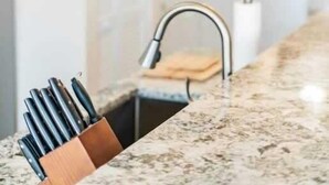 Una cucina con piano di lavoro in granito, tagliere e illuminazione a sospensione.