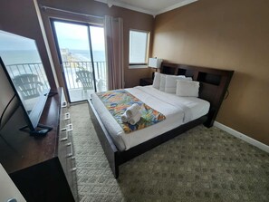 A hotel room with a bed, a desk with a computer, a window with a view, and a balcony.