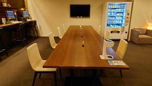 A conference room with a long table, white chairs, a TV, vending machines, and a sofa. - First Cabin Haneda Terminal 1 (Tokyo)