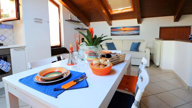 Comedor con mesa blanca, mantel individual azul y cesta naranja.