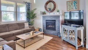A living room with a fireplace, a television, a sofa, and a coffee table. - Beautifully appointed home, ADA accessible and hot tub (Ocean Shores)